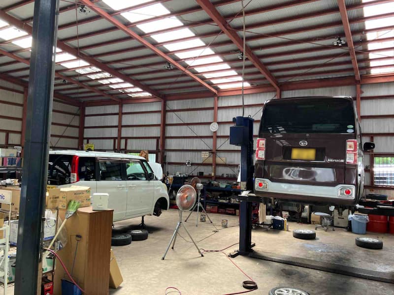 社屋の整備工場内でリフトと作業車両が配置された風景