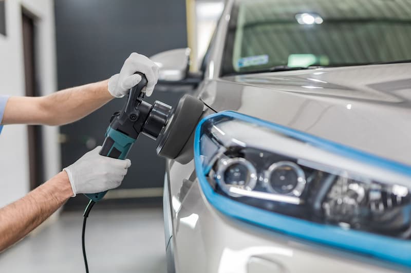 作業員が車体を電動研磨している作業風景