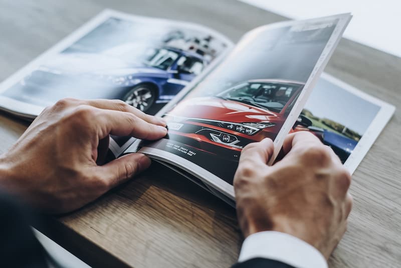 車のカタログを手に持って読んでいる男性の手元