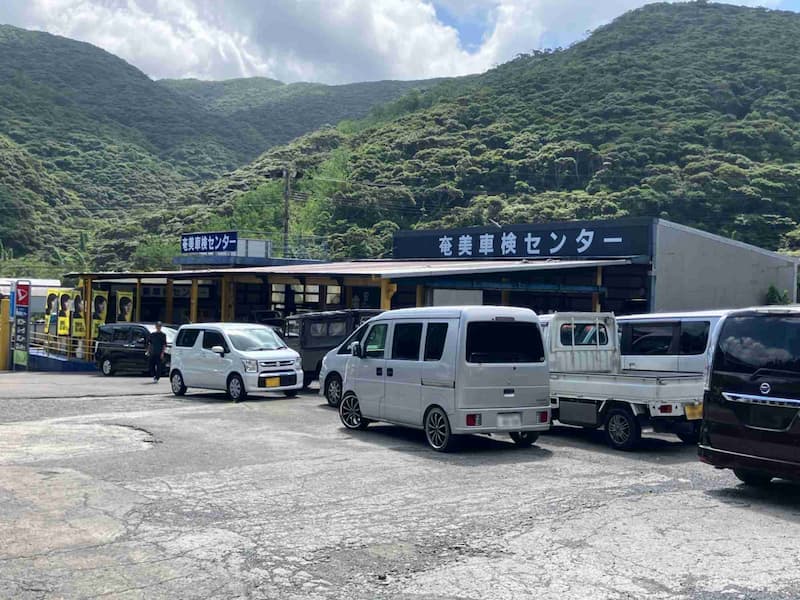 山間の奄美車検センターの駐車場に停められた複数の車両