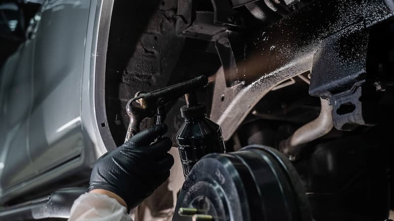自動車整備工場で防腐処理スプレーを使用する様子