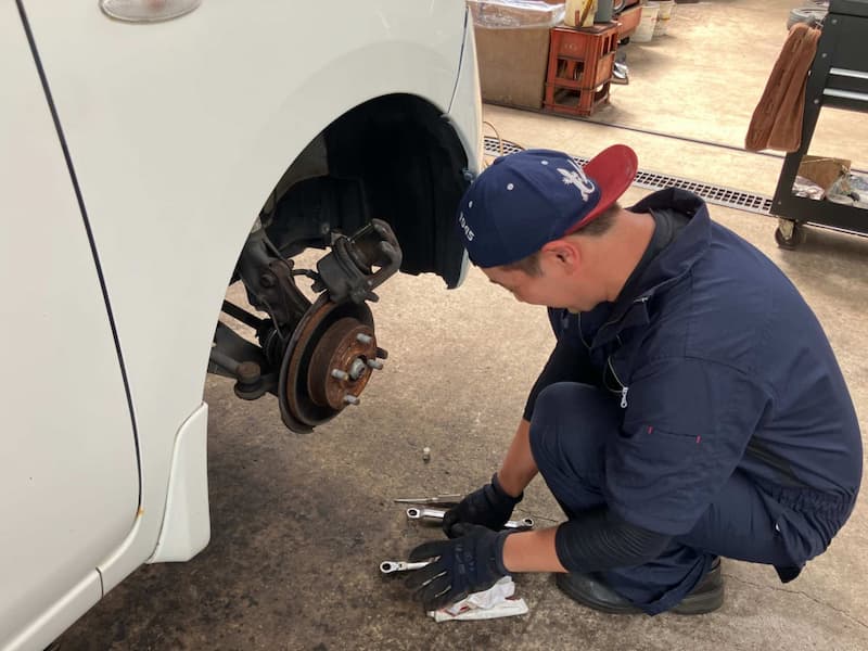 青い制服を着た整備士による車両メンテナンス作業