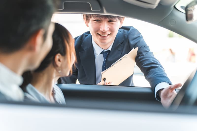 車内のお客様に資料を使って説明をする男性営業マン