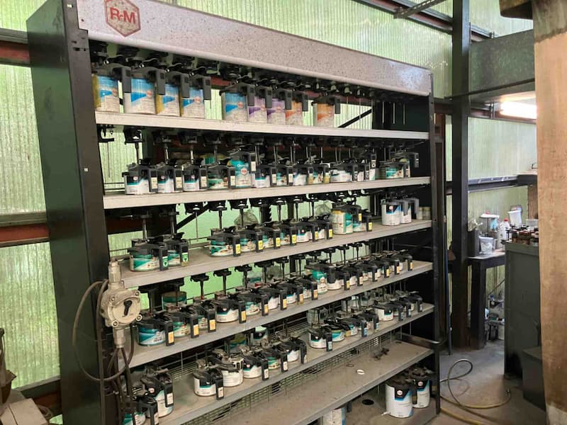 整備工場内にあるカラー塗料の棚システムに収納された自動車用スプレー塗料