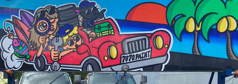 ヤシの木と夕日を背景にした壁に書かれた赤い車の絵